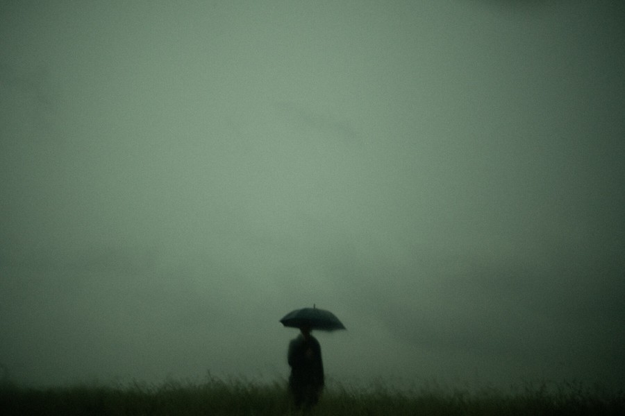 Silhouetted man under umbrella and dark moody skies